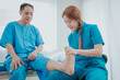 Asian female physiotherapist helping senior older woman stretching hamstring, Rehabilitation physiotherapy, elderly. Causes knee pain, swelling, redness, stiffness in knee, clunking noise in knee.