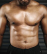 © peopleimages.com - Closeup, shine and man with abs, stomach and flex body with bodybuilding journey and show progress. Gym, guy and athlete with tummy and shirtless with challenge, fitness for six pack and endurance
