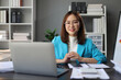 © Kainnika - Asian businesswoman working on documents with laptop in office.