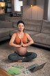 A focused adult pregnant woman meditating in the living room and concentrating on her breathing