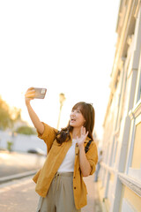 Wall Mural - Traveler asian woman in her 30s making a livestream and sefie with a smartphone enjoying travel in Bangkok, Thailand. Journey trip lifestyle, world travel explorer or Asia summer tourism concept.