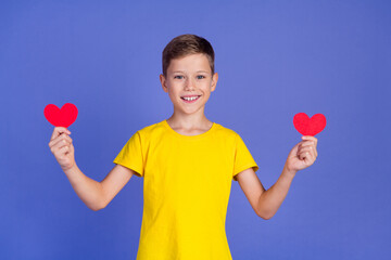 Wall Mural - Photo of cheerful adorable cute small boy wear stylish yellow clothes hold red paper postcards isolated on purple color background