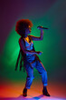 © Lustre Art Group  - Portrait of young African-American woman dressed retro attire engaging in song in neon light against gradient background. Concept of art, music, hobby, classical music and modern lifestyle. Ad