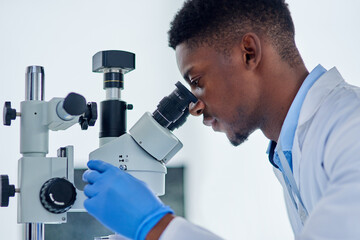 Science, research and black man with microscope for analysis, investigation or medical engineering in laboratory. Biotech, lab technician or scientist checking vaccine sample for pharmaceutical test.