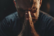 Close up of man praying with hands clasped together against dark background, Black background. Concept for religion, faith, prayer and spirituality
