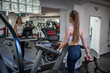 Young woman going on treadmill machine in fitness club. 