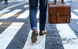 Fototapeta Londyn - Close up of legs Businessman crossing the street on crosswalk and holding a laptop bag in the city.