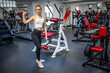 Young woman holds dumbbells in her hands and works out in the gym performing an exercise