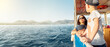 Mother with children enjoys travel on boat sailing in sea past coast of Marmaris against mountains wide shot