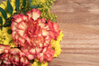bouquet of red and yellow flowers, with red snapdragons in the foreground and yellow flowers in the background, lying as a decoration on wooden surface, space for text
