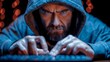 A bearded man in a hood sits and works behind a computer hacker