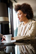 Attractive young black business woman drinking a coffee and using a digital tablet during a break