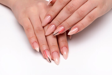 Wall Mural - Beige manicure on sharp long nails with black-orange stripes close-up on a white background. Nude manicure.