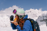 Fototapeta  - Woman skier snowboarder having lunch outdoors while skiing at ski resort in high mountains
