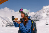 Fototapeta  - Woman skier snowboarder having lunch outdoors while skiing at ski resort in high mountains