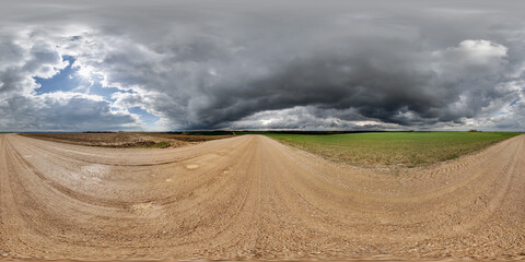 Wall Mural - hdri 360 panorama on wet gravel road among fields in spring nasty day with storm clouds in equirecta
