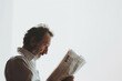 tranquility of a man reading a newspaper, with a close-up shot against a white background, inviting viewers to appreciate the peacefulness and intellectual stimulation of the readi