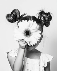 Wall Mural - A little girl covers her face with a large flower. Black and white photo.
