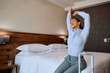 Smiling businesswoman stretching on  bed in hotel room.