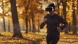 Young person in sportswear and virtual reality headset training and running outdoor in Autumn park.