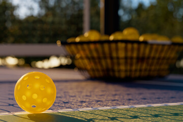 Wall Mural - Close up of a pickleball ball on a court at sunset 3D rendering.