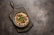 Royal mushroom risotto in a bowl on a wooden cutting board, dark rustic background. Top view, flat lay, copy space.