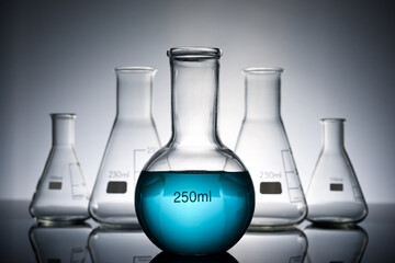 Sticker - Glass flasks placed in a laboratory table with blue liquid