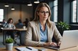 © ThomasLENNE - Portrait confident businesswoman working at laptop in office