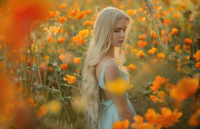 A Young Woman With Long Blonde Hair Stands In Front Of An Orange And Yellow Flower Wall, Surrounded By Flowers That Fall From The Sky