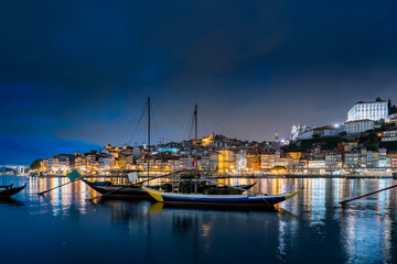 Wall Mural - Porto, Portugal old town on the Douro River with traditional rabelo boats at night. With wine barrels from the port on the Douro River, Ribeira I in the background, Porto, Portugal.