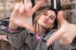 Attractive woman with a lovely smile making a frame gesture with her fingers framing her face, blowing kiss. Woman posing on selfie photo looking at camera walking outdoors in urban cafe.
