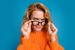 Photo of funny woman wear stylish orange clothes look suspiciously spectacles isolated on blue color background