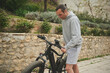 © Taras Grebinets - Caucasian muscular man pushing electric mountain bike in the city. People. Healthy active lifestyle. Sport. Adventure travel on bicycle. Using el-bicycle as eco-friendly transport