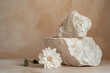 White stones podium with flower on beige textured background. Minimalistic composition, object display mockup.