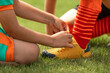 Soccer Boy Helping Teammate to Tie Laces. Friends in Sports Team. Kids Play Football Game Wearing Soccer Cleats