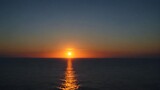 Fototapeta  - Out of focus sun setting over the ocean glowing orange with dark blue background