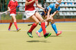 Field hockey female player makes shot before opponents legs