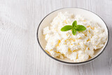 Fototapeta Młodzieżowe - Cottage cheese in a plate on a white table, with copy space for text