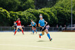 Young field hockey player run on the pitch in attack.