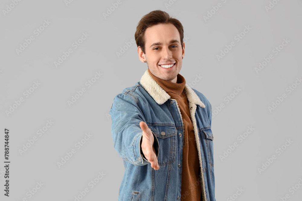 Young man reaching out for handshake on light background