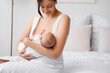 Happy mother breastfeeding her little cute baby in bedroom