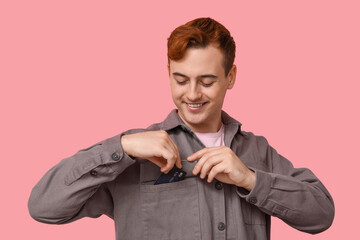 Sticker - Young man putting credit card into pocket on pink background