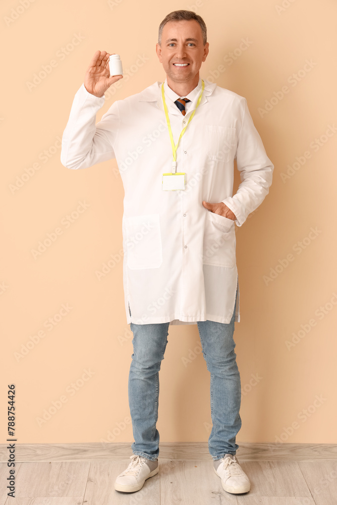 Mature doctor with pill bottle near beige wall
