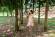 Young pretty woman walking among trees in old park of small town