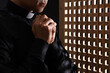 © Pixel-Shot - Young priest praying in confession booth, closeup