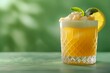Penicillin cocktail with frothy top and lemon wheel garnish on a green background
