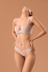 Sticker - Beautiful young woman in stylish beige underwear on brown background