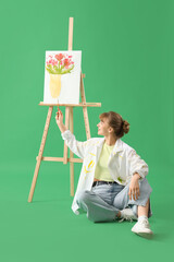 Poster - Female artist with brush pointing at painting on green background