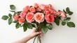   A single hand holds a bouquet of peach-colored roses against a pristine white backdrop, their vibrant hue contrasted by the verdant green leaves