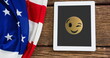 A tablet displaying winking emoji rests beside American flag